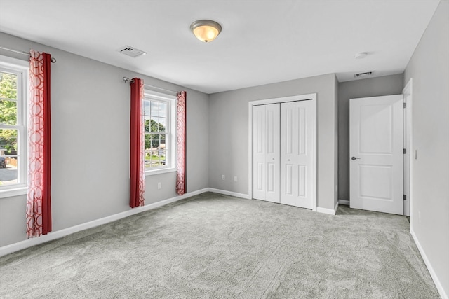 unfurnished bedroom featuring carpet flooring, multiple windows, and a closet