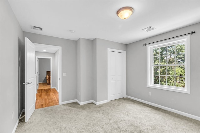 unfurnished bedroom with light carpet and a closet