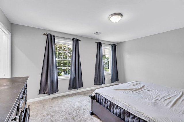 bedroom featuring light carpet and multiple windows