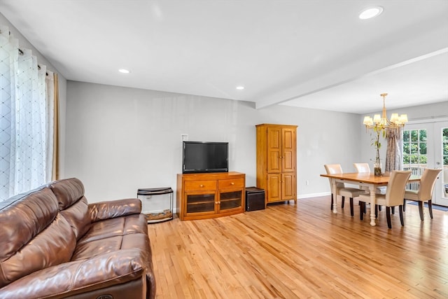 living room featuring light wood-type flooring, a chandelier, and beam ceiling