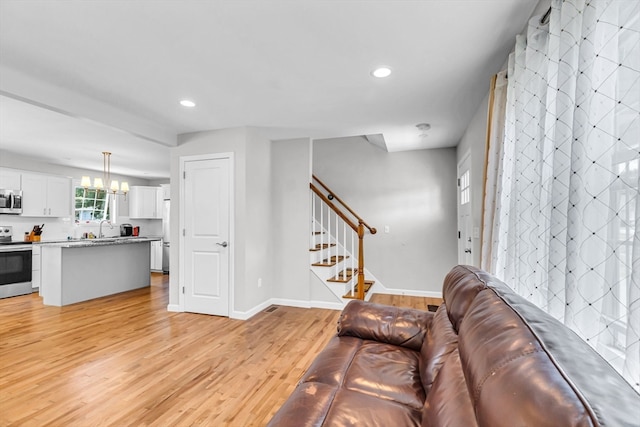 living room with light wood-type flooring, a notable chandelier, and sink