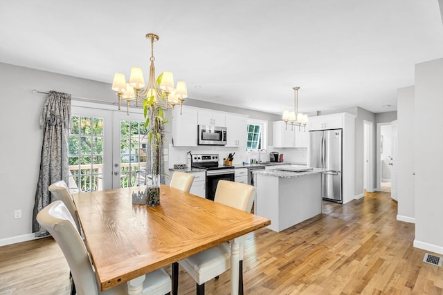 dining room with an inviting chandelier, sink, light hardwood / wood-style flooring, and french doors