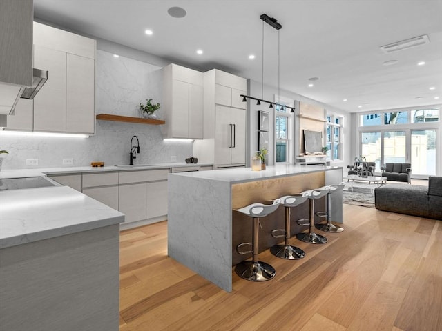 kitchen featuring a center island, visible vents, light wood-style floors, a sink, and modern cabinets