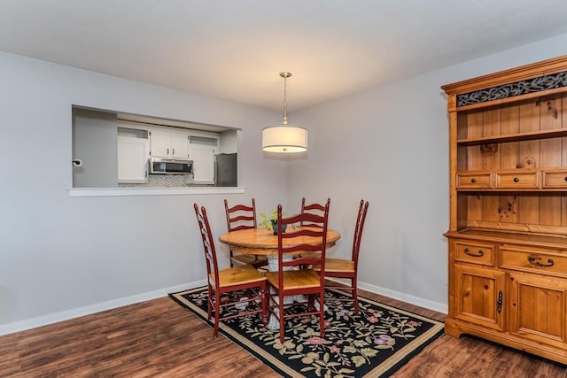 dining space featuring dark wood-style flooring and baseboards