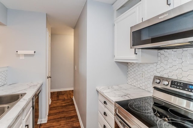 kitchen featuring white cabinetry, baseboards, appliances with stainless steel finishes, decorative backsplash, and light stone countertops