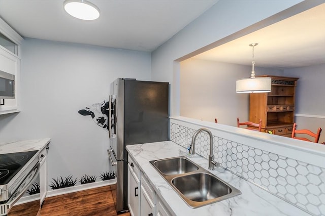 kitchen with appliances with stainless steel finishes, dark wood-type flooring, white cabinetry, a sink, and light stone countertops