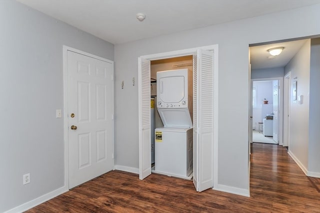 washroom with stacked washing maching and dryer, baseboards, laundry area, and wood finished floors