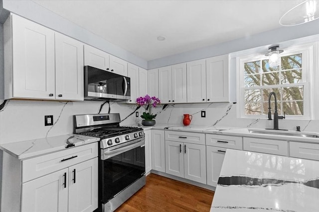 kitchen featuring light stone counters, stainless steel appliances, sink, white cabinets, and dark hardwood / wood-style floors