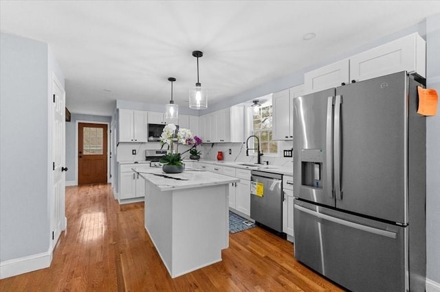 kitchen featuring a center island, white cabinets, light hardwood / wood-style flooring, decorative light fixtures, and stainless steel appliances