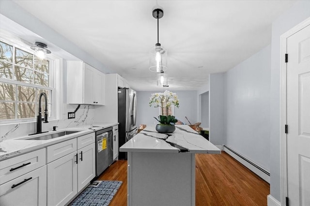 kitchen featuring stainless steel appliances, a baseboard heating unit, a center island, white cabinetry, and hanging light fixtures