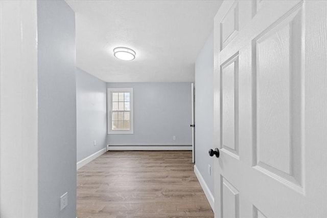 empty room with baseboard heating and light hardwood / wood-style floors