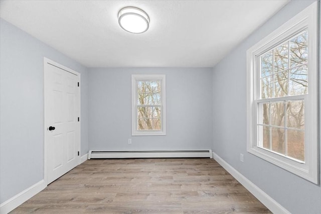 empty room with light wood-type flooring and a baseboard heating unit