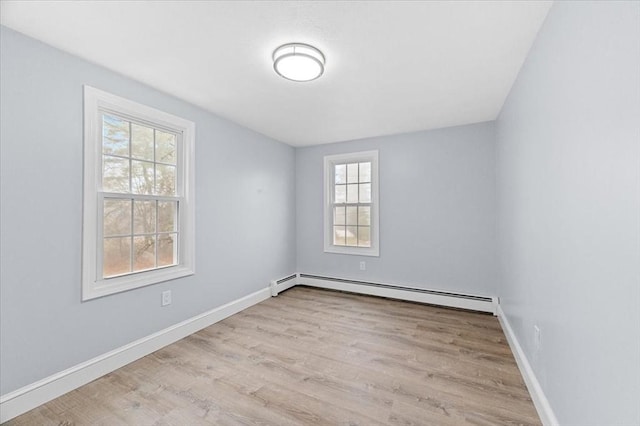 unfurnished room with light wood-type flooring and a baseboard heating unit