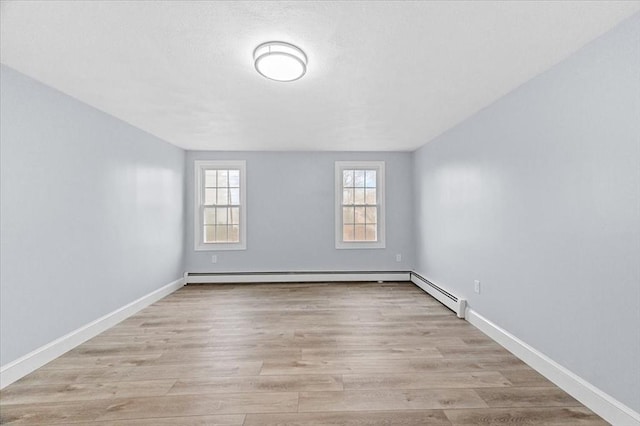 spare room with a healthy amount of sunlight, light hardwood / wood-style floors, and baseboard heating