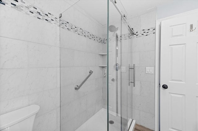 bathroom featuring a shower with shower door and toilet