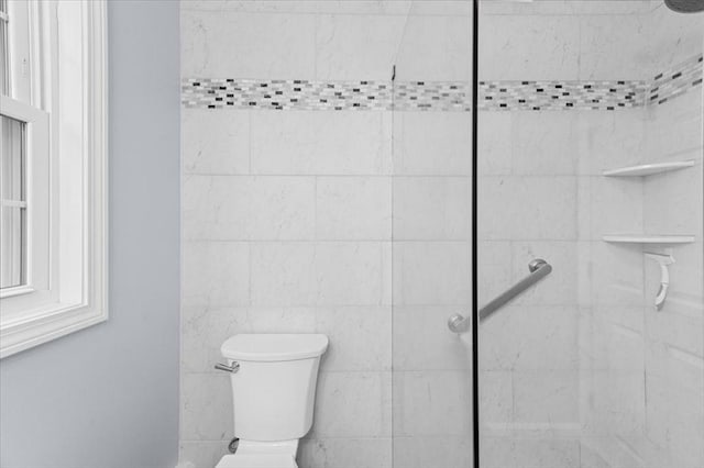 bathroom featuring a tile shower and toilet