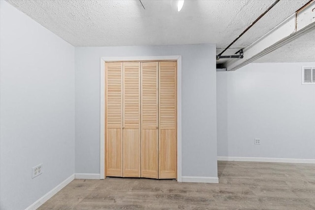 unfurnished bedroom featuring a textured ceiling, light hardwood / wood-style flooring, and a closet