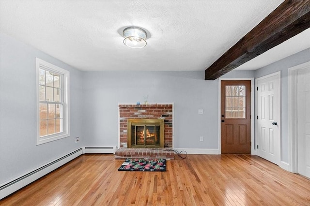 unfurnished living room featuring beamed ceiling, a fireplace, a baseboard radiator, and light hardwood / wood-style flooring