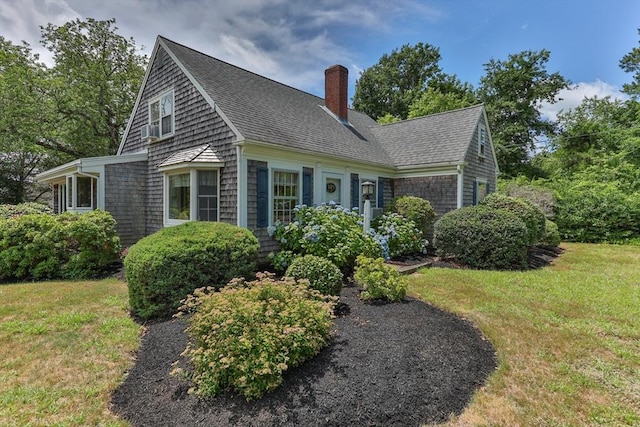 view of side of property featuring a chimney, a lawn, and a shingled roof