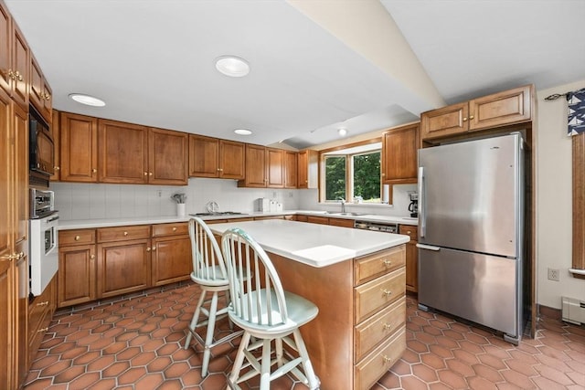kitchen featuring freestanding refrigerator, white oven, vaulted ceiling, light countertops, and a kitchen island
