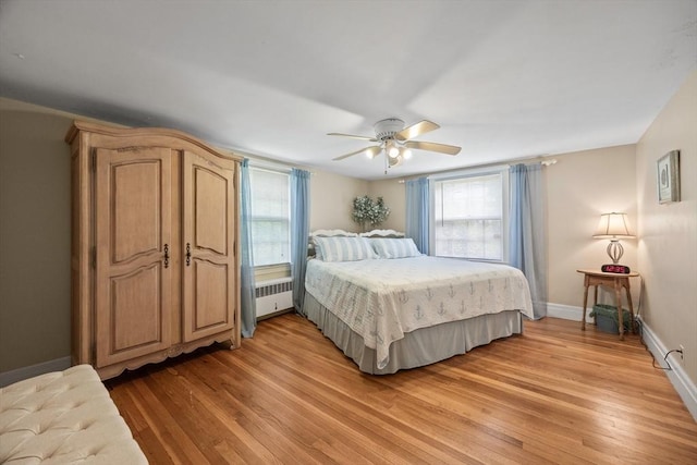 bedroom featuring radiator heating unit, light wood finished floors, baseboards, and a ceiling fan
