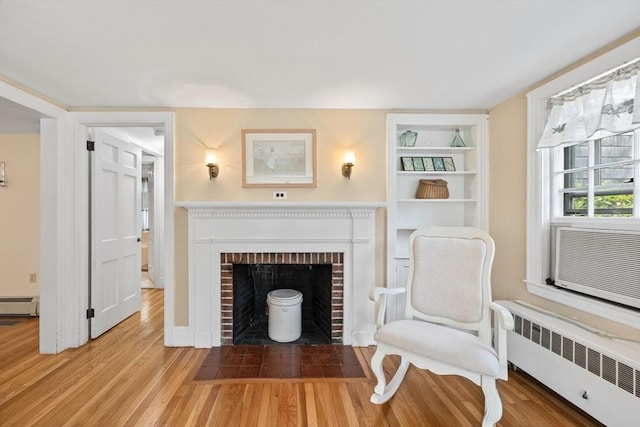 unfurnished room featuring radiator, a baseboard radiator, wood finished floors, and a fireplace