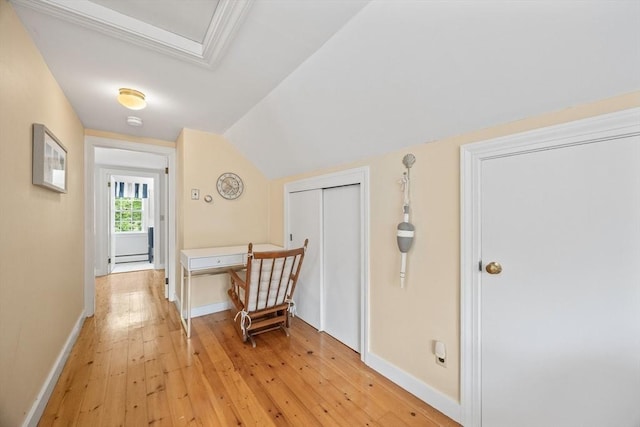 hall featuring light wood finished floors, baseboards, vaulted ceiling, and a baseboard heating unit