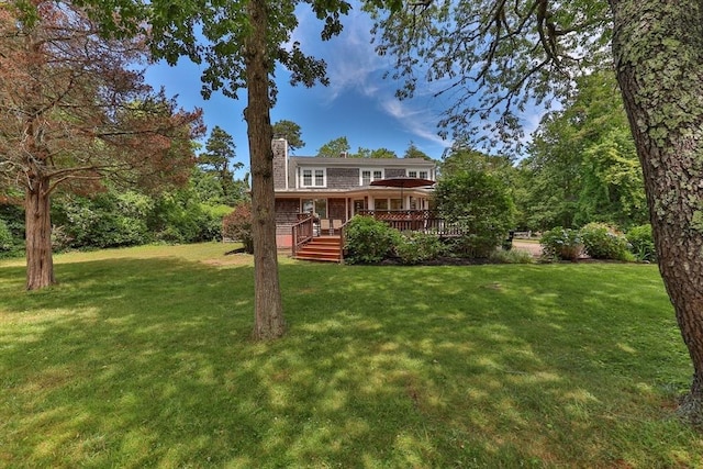 back of house with a deck, a yard, and a chimney