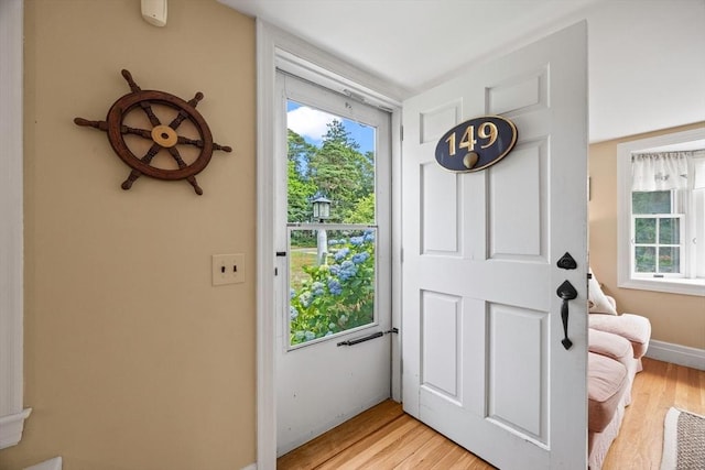 entryway featuring light wood-type flooring, plenty of natural light, and baseboards