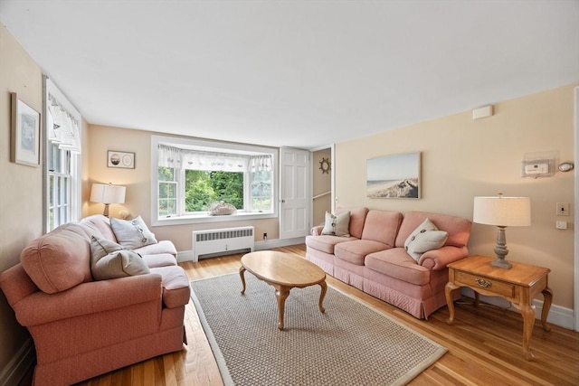 living area with radiator heating unit, light wood finished floors, and baseboards