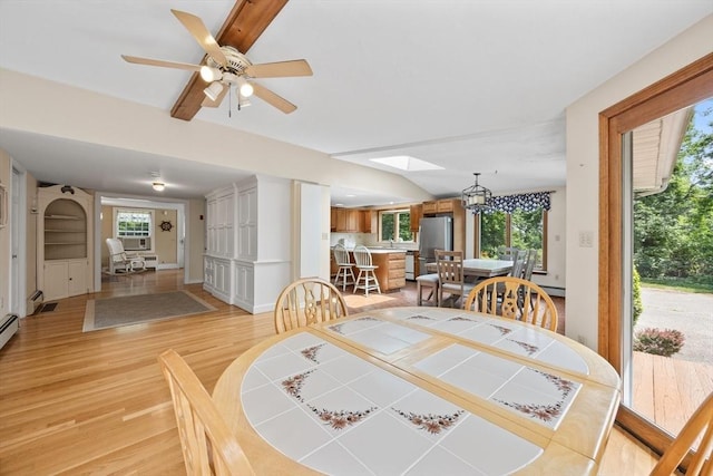 dining space with light wood-style floors, a skylight, a ceiling fan, and a chandelier