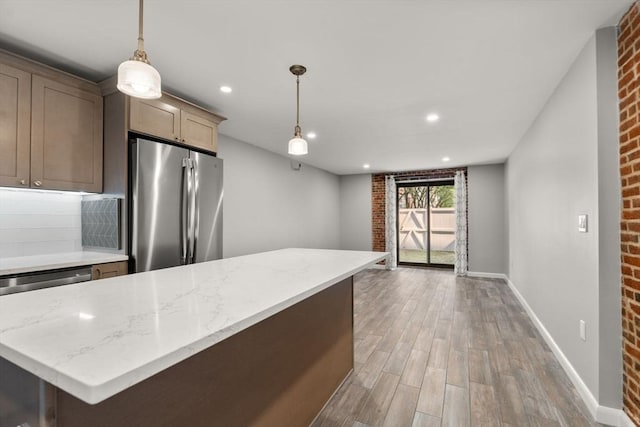 kitchen with freestanding refrigerator, decorative light fixtures, and light stone counters