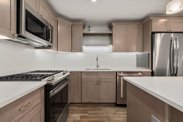 kitchen featuring appliances with stainless steel finishes, decorative backsplash, a sink, and dark wood-type flooring