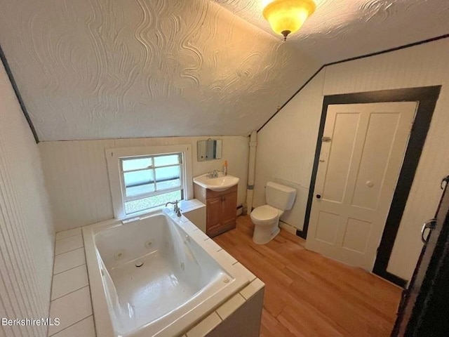 bathroom featuring vanity, toilet, a whirlpool tub, wood finished floors, and lofted ceiling
