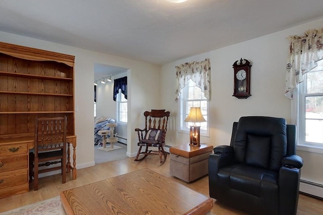 sitting room with a baseboard radiator, baseboards, and wood finished floors