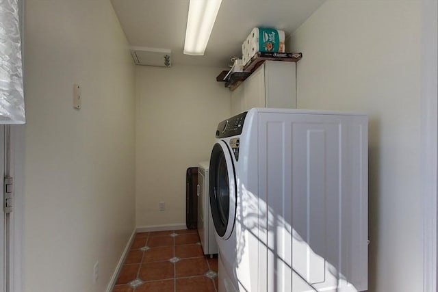 laundry area featuring laundry area, washing machine and dryer, baseboards, and tile patterned flooring