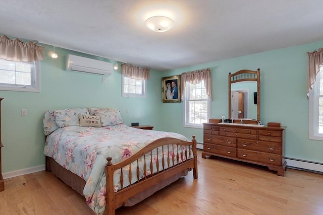 bedroom with light wood-type flooring, a baseboard heating unit, baseboards, and a wall mounted air conditioner