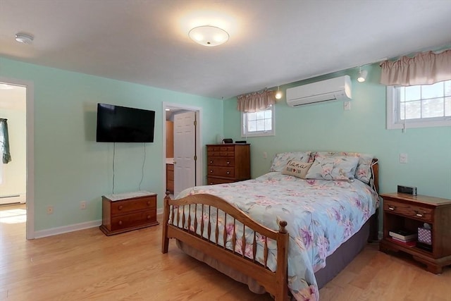 bedroom with a baseboard radiator, a wall unit AC, light wood-style flooring, and baseboards