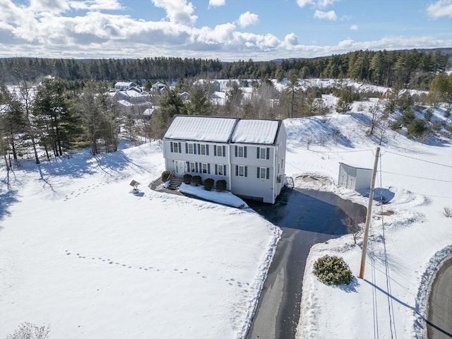 snowy aerial view featuring a wooded view