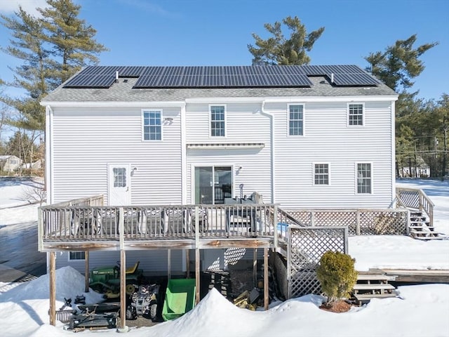 snow covered property featuring solar panels, a deck, and stairs