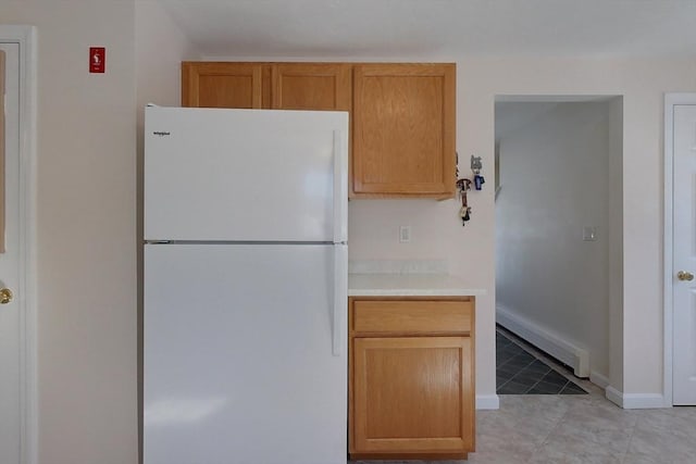 kitchen featuring light countertops, light tile patterned flooring, freestanding refrigerator, and baseboards