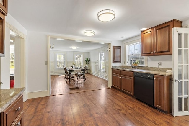 kitchen featuring black dishwasher, light stone countertops, dark wood-style floors, and a sink