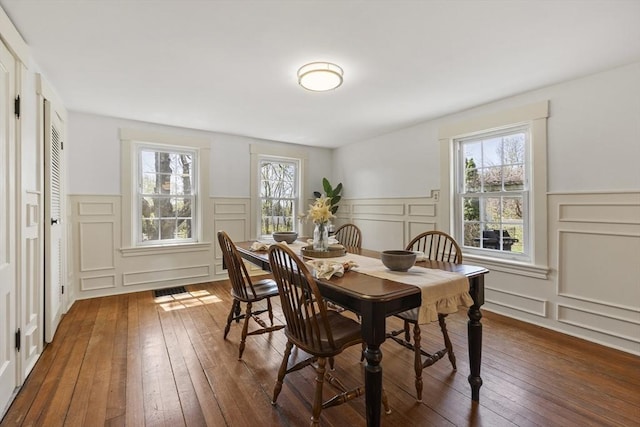 dining area with dark wood-type flooring, plenty of natural light, and a decorative wall