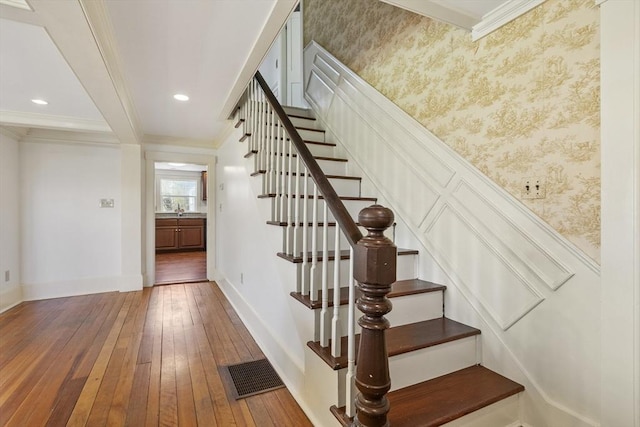 staircase featuring crown molding, baseboards, hardwood / wood-style flooring, and visible vents