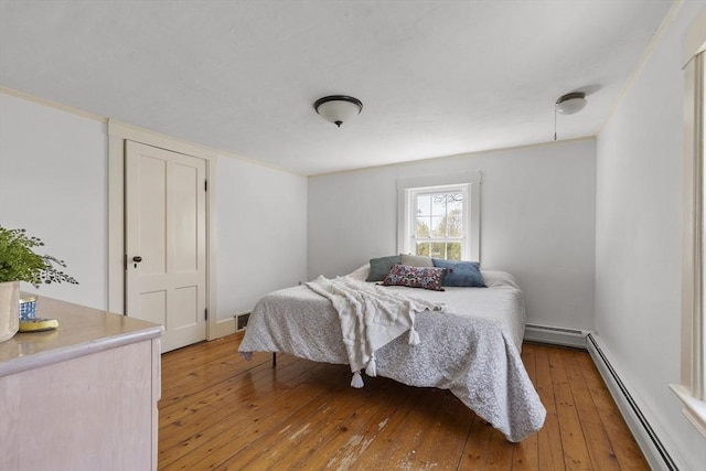 bedroom with a baseboard radiator and light wood-type flooring