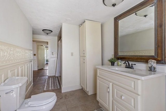 full bathroom with toilet, tile patterned floors, and vanity