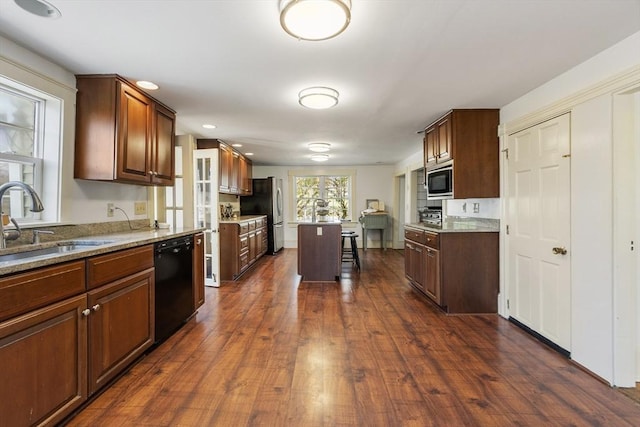 kitchen with appliances with stainless steel finishes, a kitchen bar, a sink, and dark wood finished floors
