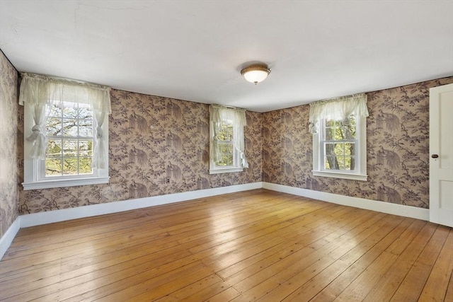 unfurnished room with baseboards, hardwood / wood-style flooring, and wallpapered walls