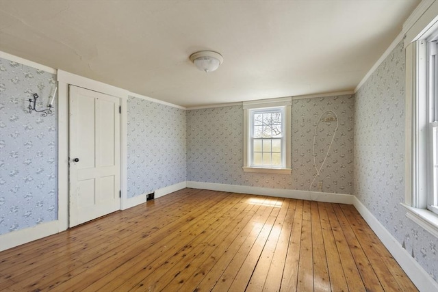 empty room featuring wallpapered walls, baseboards, and light wood finished floors