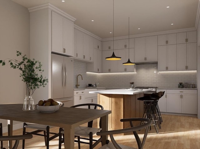 kitchen featuring light wood finished floors, white fridge, light countertops, tasteful backsplash, and a center island